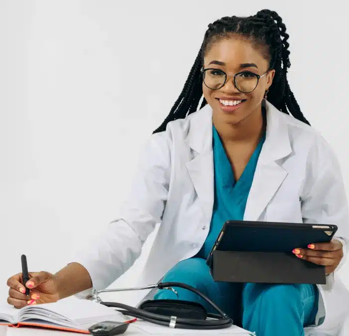 Infirmière souriante en blouse blanche utilisant un logiciel infirmier sur tablette pour gérer les dossiers médicaux
