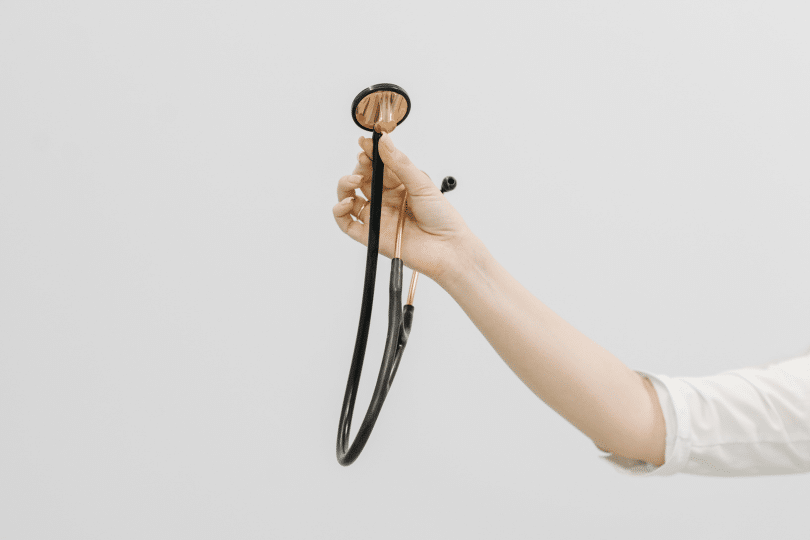 Main tenant un stéthoscope sur fond blanc