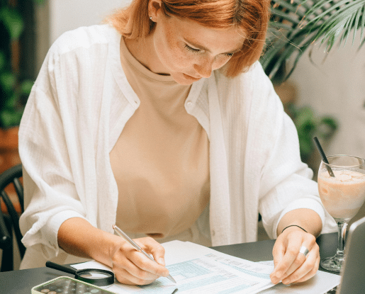 Infirmière libérale concentrée sur la gestion de sa trésorerie, remplissant des documents comptables devant son ordinateur