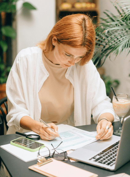 Infirmière libérale concentrée sur la gestion de sa trésorerie, remplissant des documents comptables devant son ordinateur